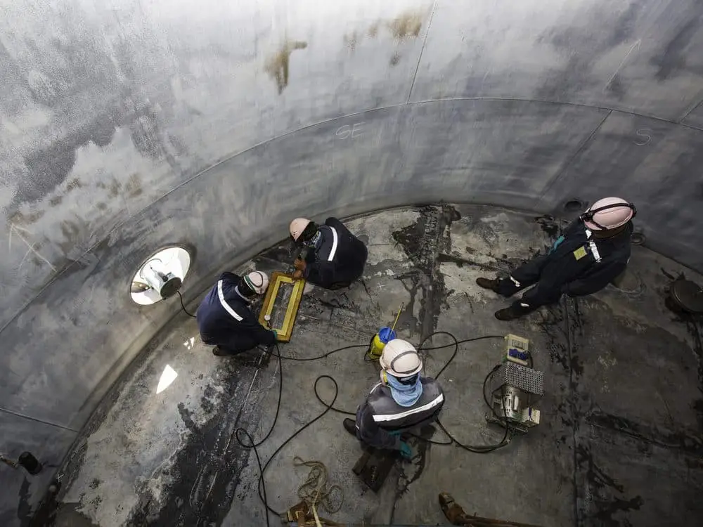 Specialist maintenance team working safely inside a large tank